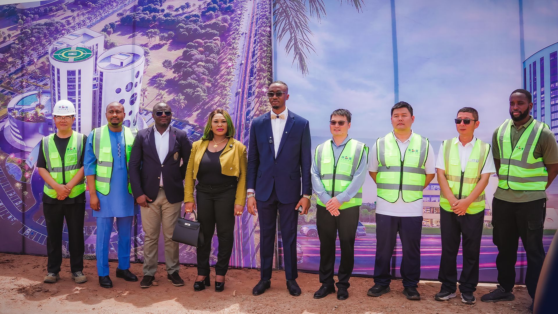 The Tri-Tower project team on site in Abuja, standing in front of the project hoarding